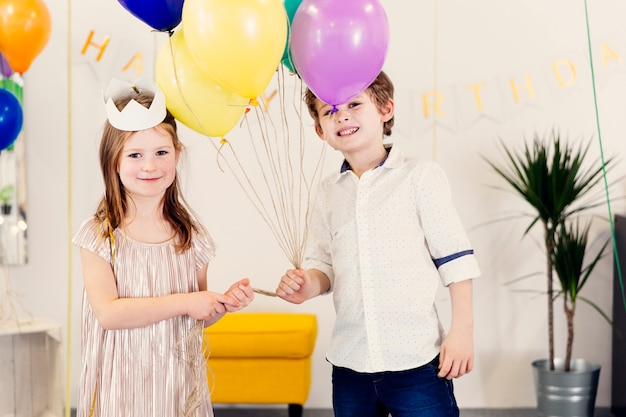 Niños con globos mirando a cámara