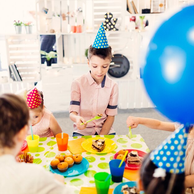 Foto gratuita niños con gorras de colores sentados en la mesa