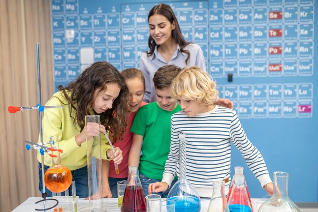 Niños haciendo experimentos químicos y maestros mirando