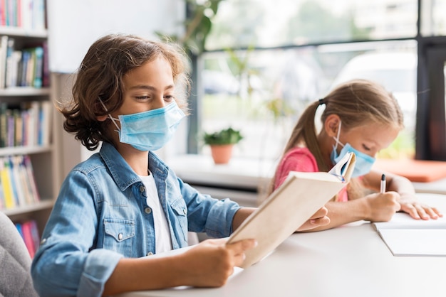 Niños haciendo sus deberes mientras usan una mascarilla