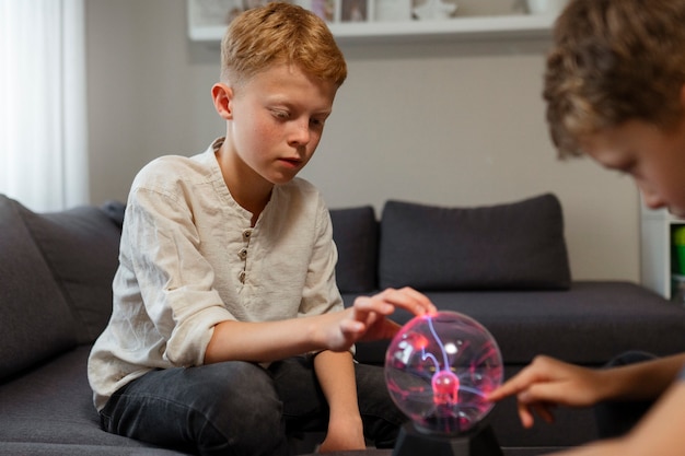 Niños interactuando con una bola de plasma.