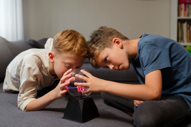 Niños interactuando con una bola de plasma.