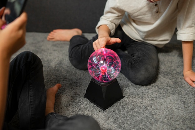 Niños interactuando con una bola de plasma.