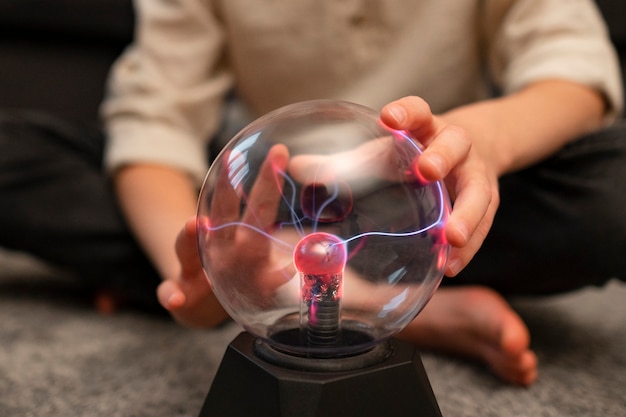 Niños interactuando con una bola de plasma.