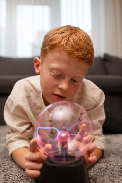 Niños interactuando con una bola de plasma.