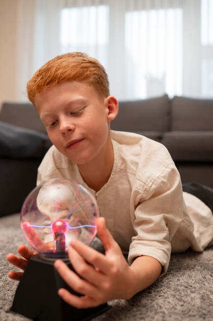 Niños interactuando con una bola de plasma.