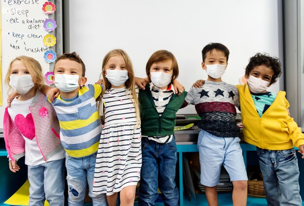 Niños de jardín de infantes con máscaras en un aula