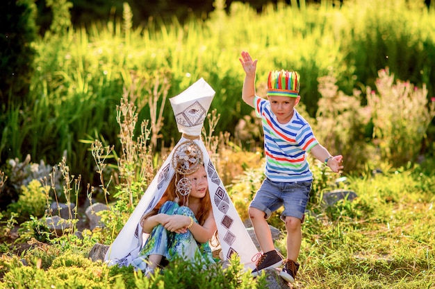 Los niños juegan como aborígenes americanos en hierba verde en el campo