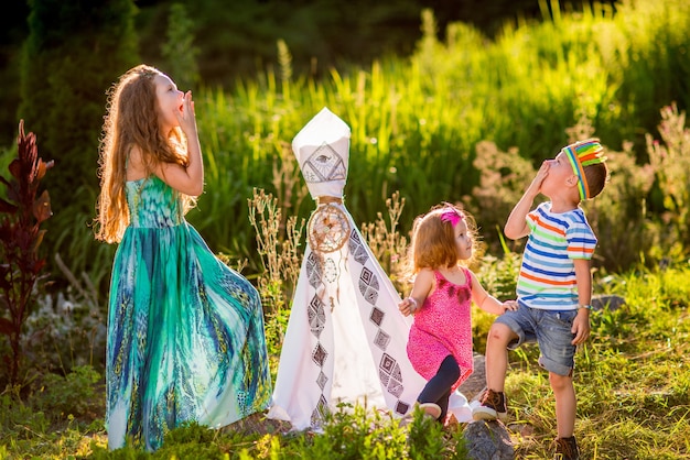 Los niños juegan como aborígenes americanos en hierba verde en el campo