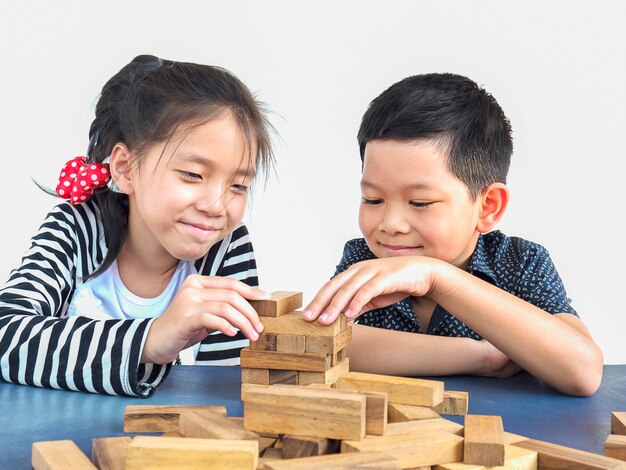 Los niños juegan jenga, un juego de torre de bloques de madera.