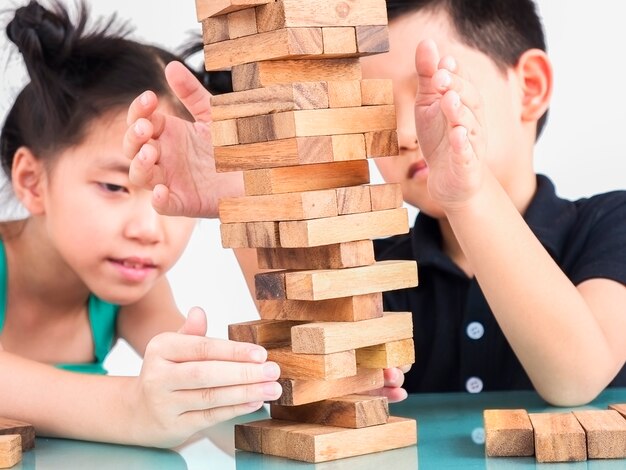 Los niños juegan jenga, un juego de torre de bloques de madera.