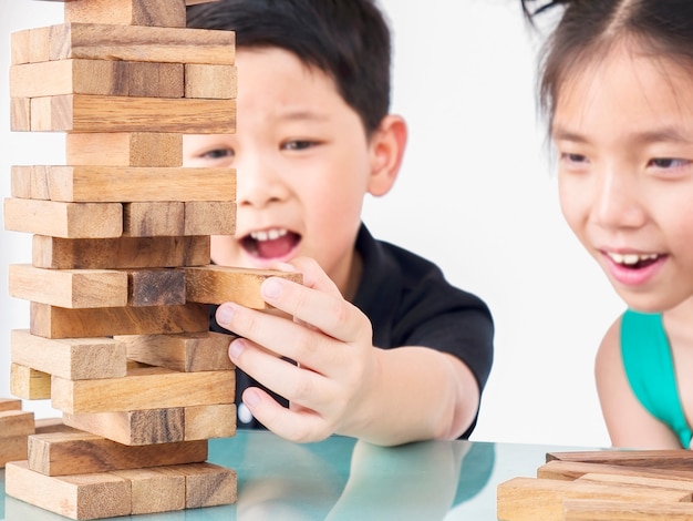 Los niños juegan jenga, un juego de torre de bloques de madera.