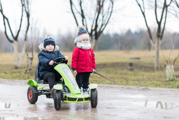 Foto gratuita niños jugando al aire libre con cochecito verde