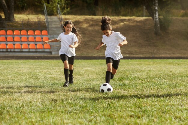 Niños jugando al fútbol supervisados por un entrenador de fútbol