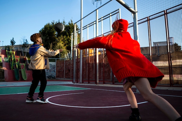 Foto gratuita niños jugando baloncesto juntos afuera.