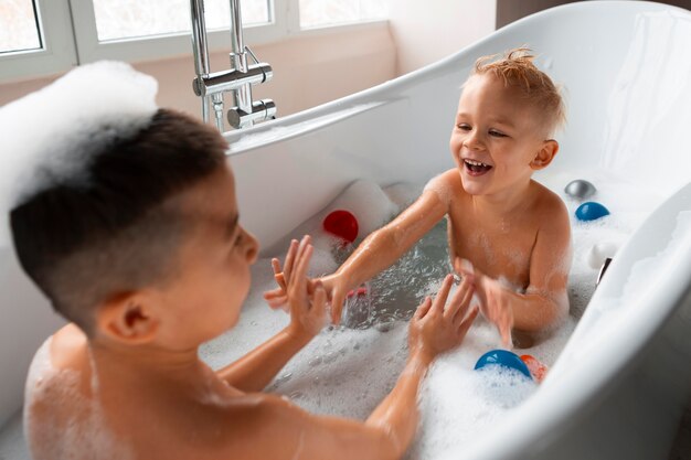 Niños jugando en la bañera con juguetes.