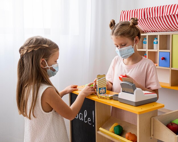 Niños jugando juntos en el interior mientras usan máscaras médicas