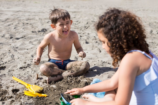 Foto gratuita niños jugando en la playa de tiro medio