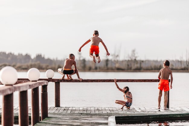 Niños jugando y saltando al agua en traje de baño.