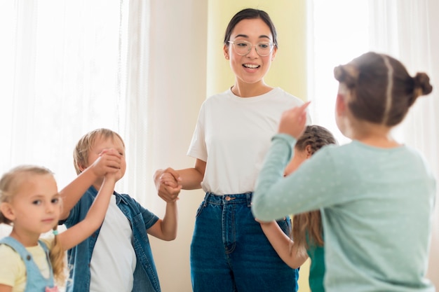 Foto gratuita niños jugando con su maestra de jardín de infantes.