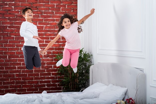 Niños juguetones saltando en la cama