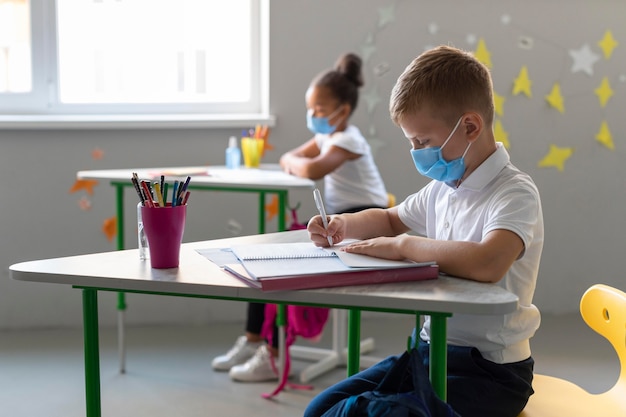 Foto gratuita los niños de lado regresan a la escuela en tiempos de pandemia