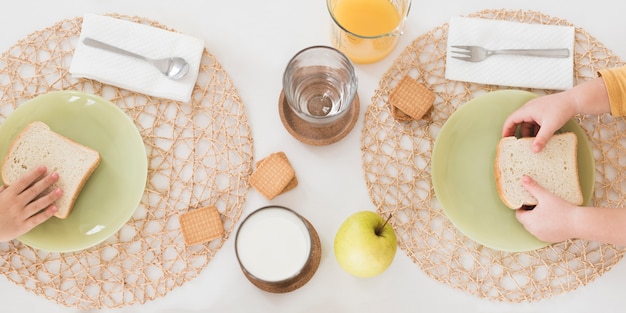 Foto gratuita niños laicos planos desayunando