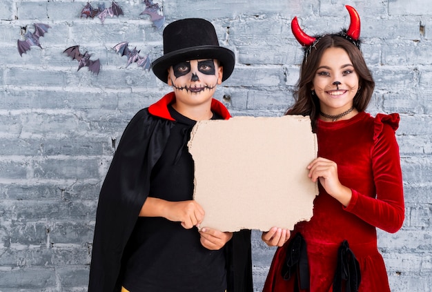 Foto gratuita niños lindos en disfraces de halloween con maqueta