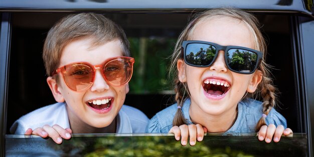 Niños lindos con grandes gafas de sol y grandes sonrisas.