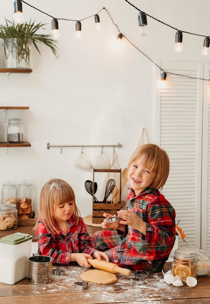 Niños lindos haciendo galletas de Navidad juntos en la cocina