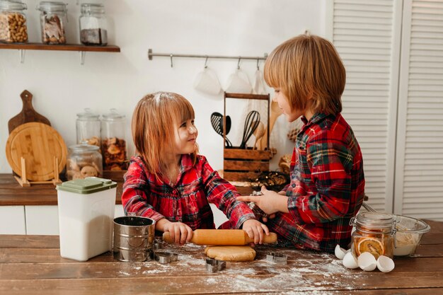 Niños lindos haciendo galletas de Navidad juntos