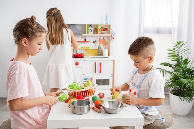 Niños lindos jugando con un juego de cocina