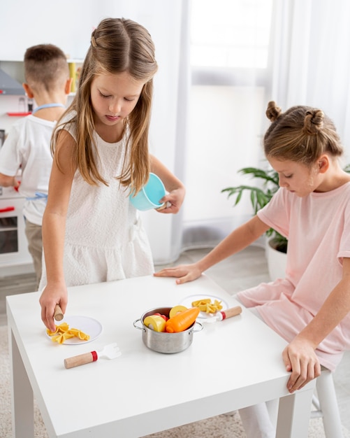 Niños lindos jugando con un juego de cocina.