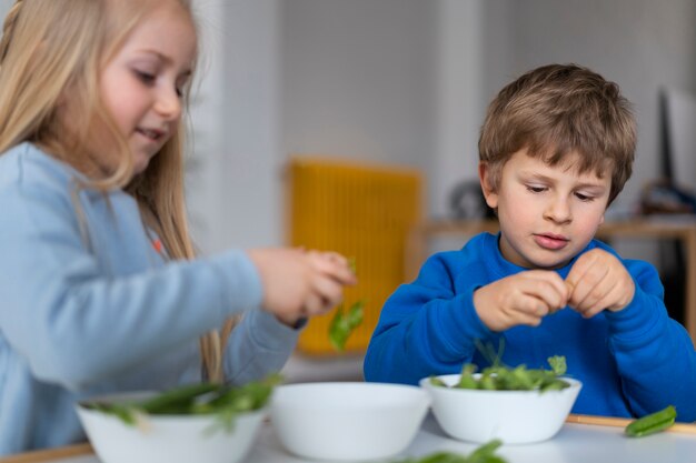 Foto gratuita niños lindos de tiro medio con comida en la mesa