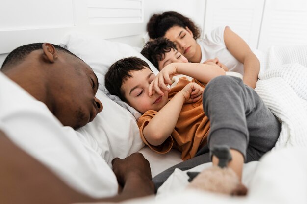 Niños lindos tratando de dormir en la cama de sus padres