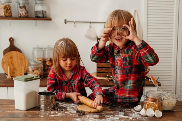 Niños lindos vista frontal haciendo galletas de Navidad juntos