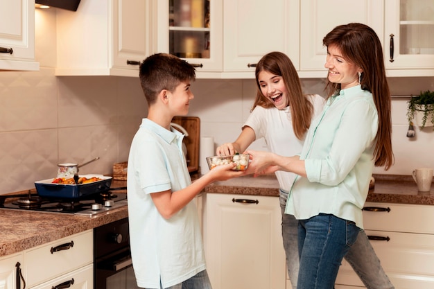 Foto gratuita niños y madre preparando comida en la cocina