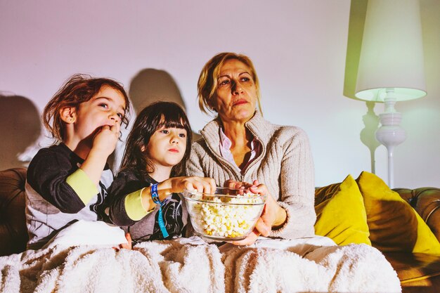 Niños y madre viendo películas con palomitas de maíz