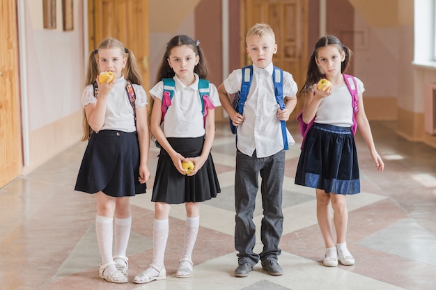 Niños con manzanas de pie en el pasillo de la escuela