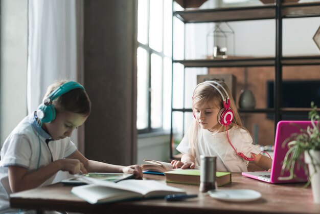 Niños en mesa con portátil y libros