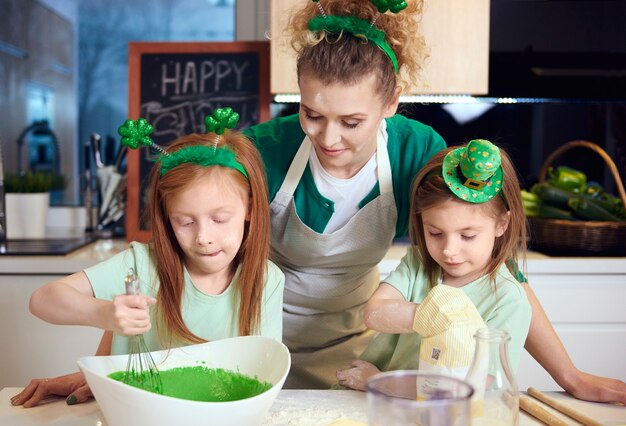 Niños mezclando glaseado de fondant bajo la supervisión de la madre.