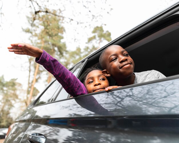 Niños mirando hacia afuera a través de la ventana de su auto