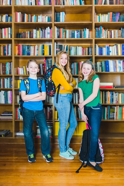 Niños con mochilas escolares de pie en la biblioteca