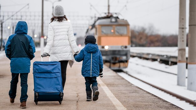 Niños y mujer de tiro completo en la estación de tren