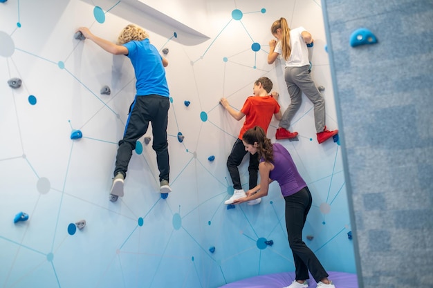 Foto gratuita niños y niñas colgando de la pared y apoyando al entrenador