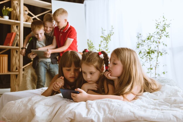 Niños y niñas usando diferentes gadgets en casa.