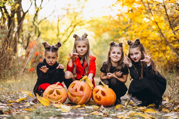 Niños niñas vestidas con disfraces de halloween al aire libre con calabazas