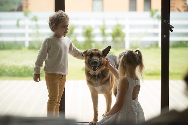 Niños niño y niña jugando con perro entrando a la casa