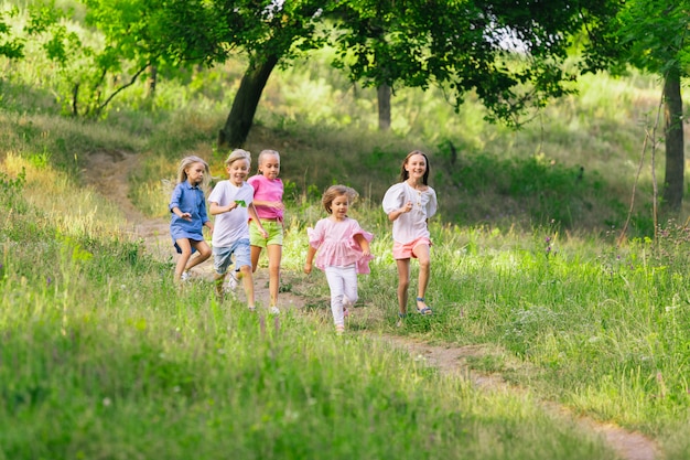 Niños, niños corriendo en la pradera a la luz del sol de verano.