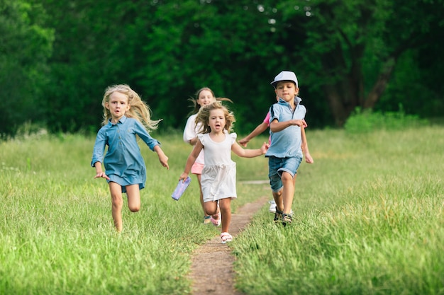 Niños, niños corriendo en la pradera a la luz del sol de verano.